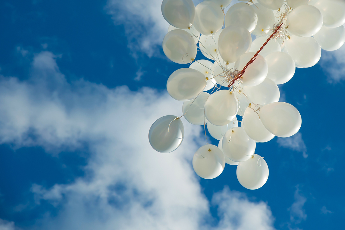 a massive bunch of balloons floating away into the sky - balloon releases are increasingly banned because they endanger animals