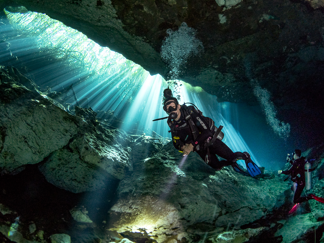 Two divers explore the cenotes which are underwater caverns and an attraction that makes Cancun one of the best May vacations