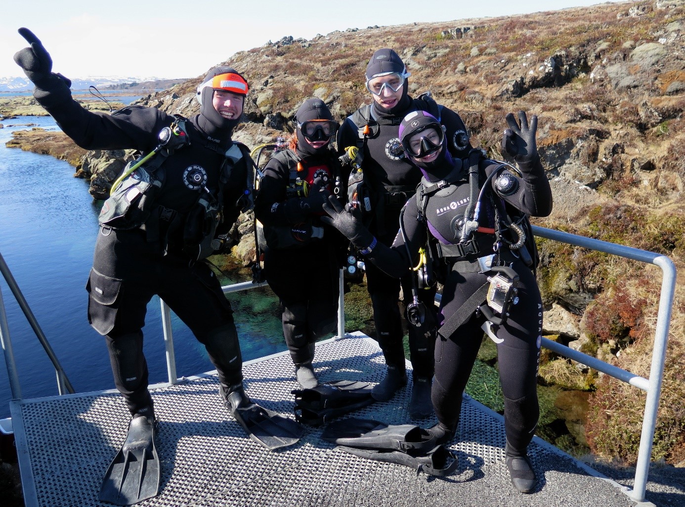 A group of divers on the surface before diving in dry suits on a lake in the mountains
