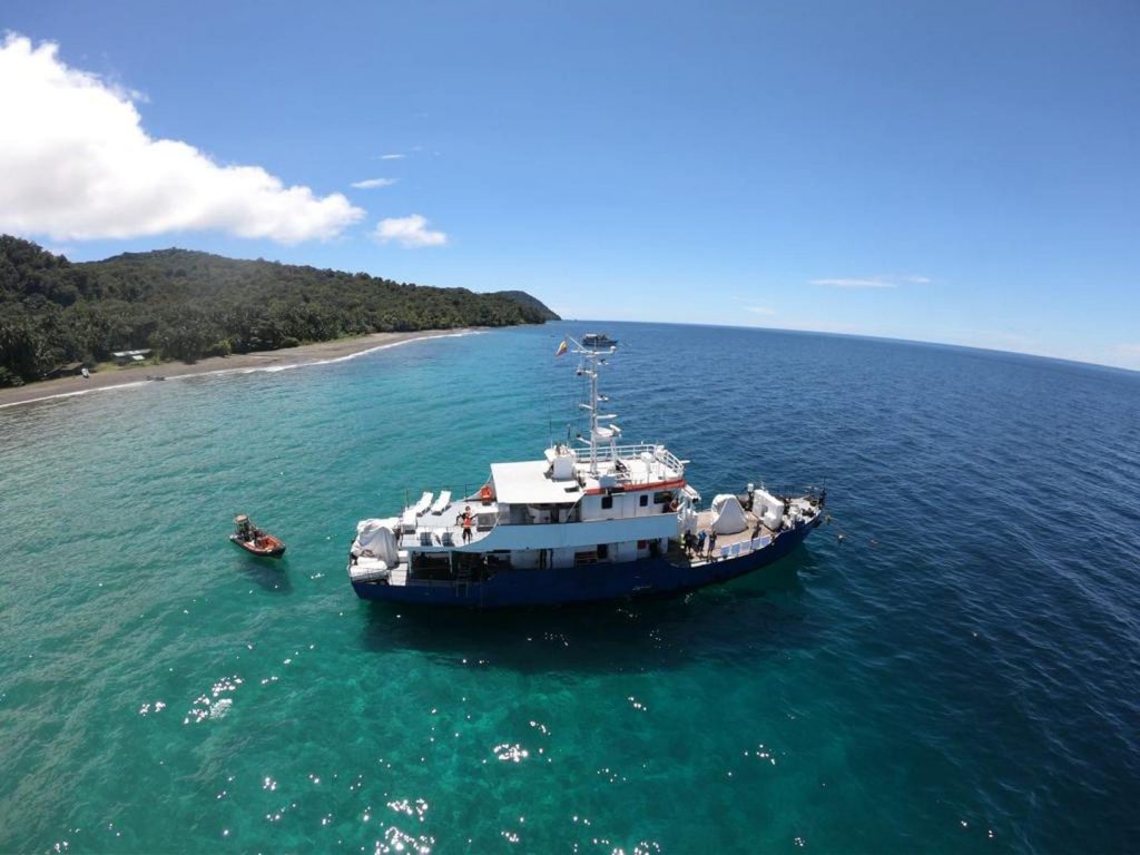 The Ferox liveaboard anchored off a beach with a tender attached to the back of the boat
