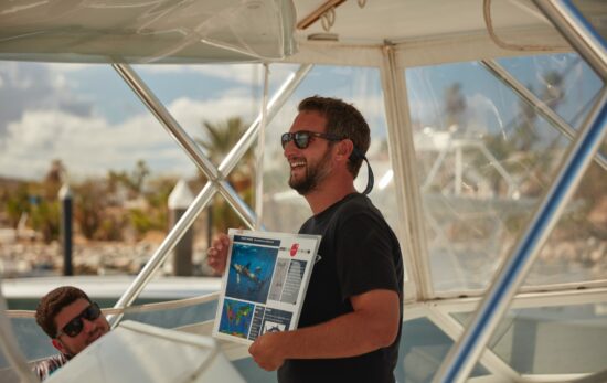 A PADI Pro delivers a dive briefing on a boat before a dive