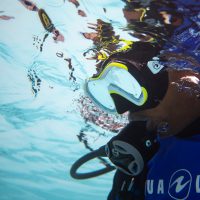 A diver looks underwater with a regulator in his mouth