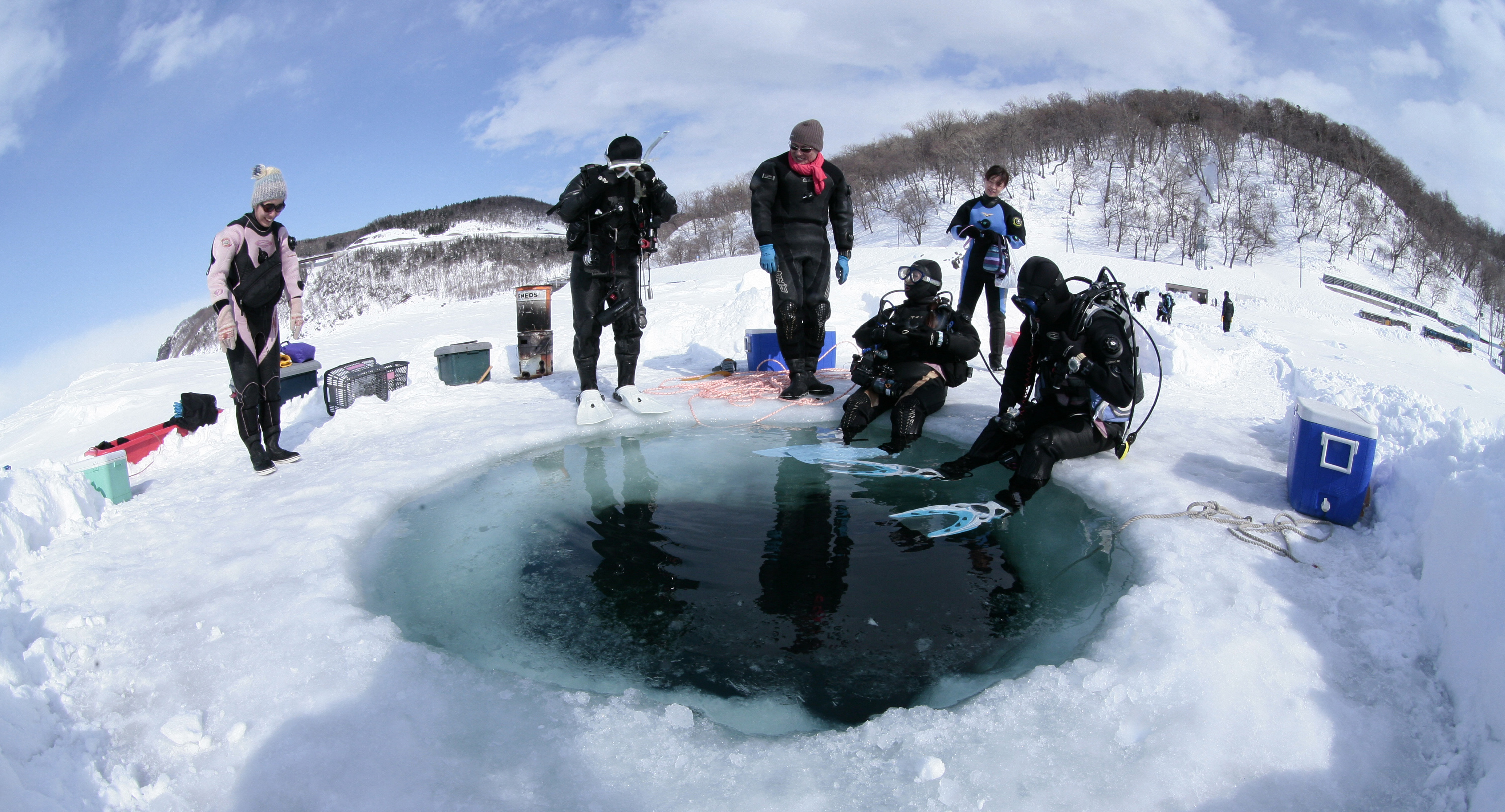 Shiretoko-ice-diving Divers waiting around the hole in the ice before they take the plunge.