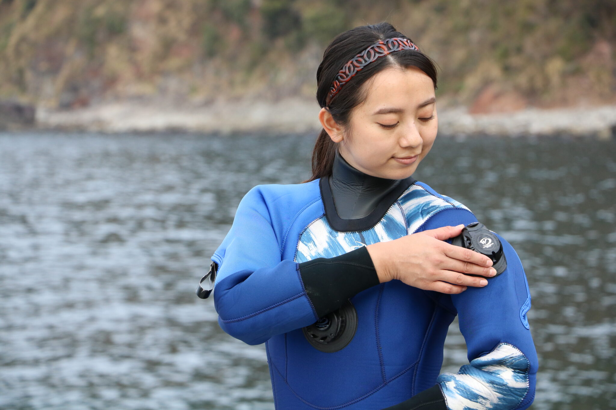 Diver fingering the exhaust valve of a dry suit.