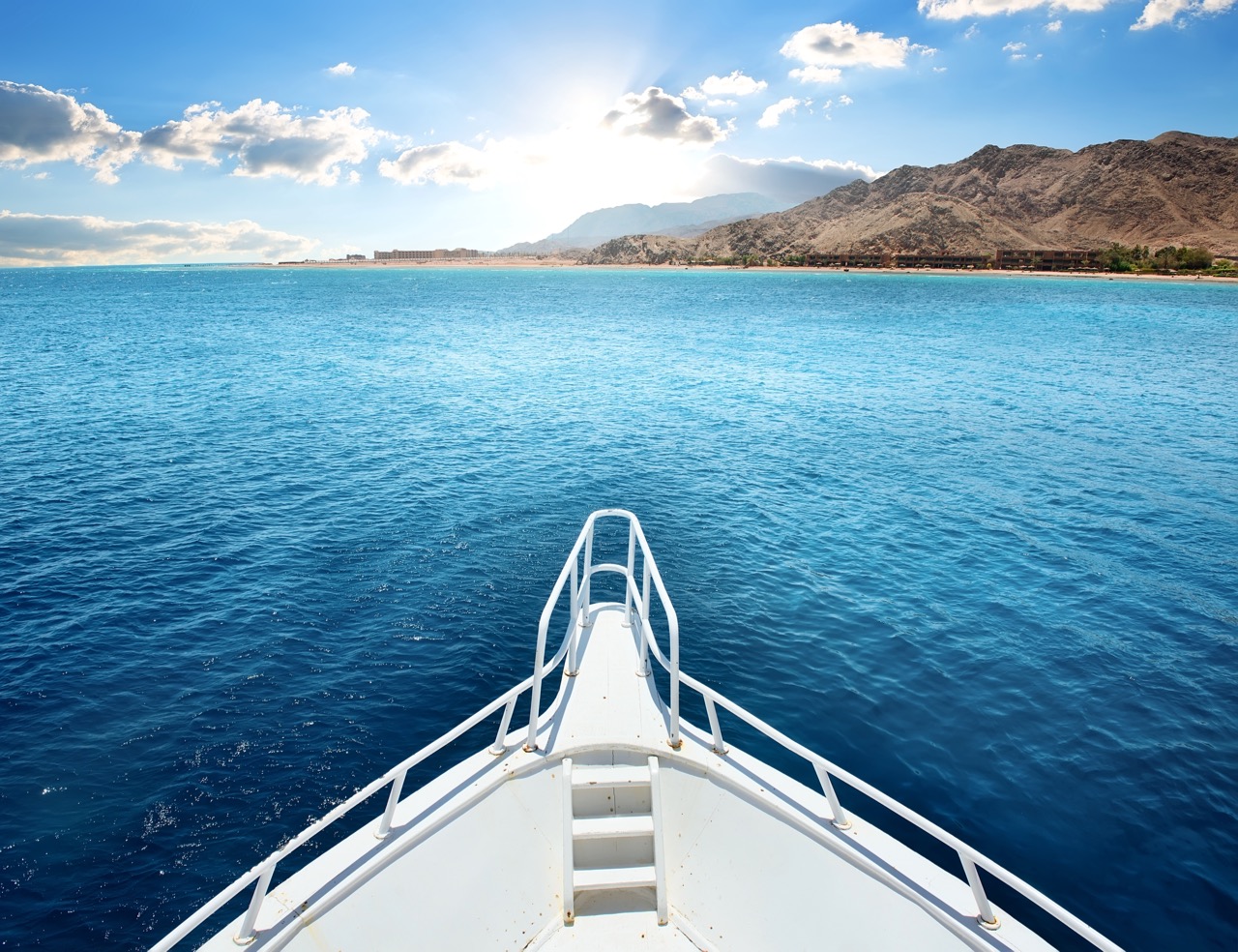 The bow of a boat with blue sea and sky on the horizon, which is a sight to be expected when traveling on scuba liveaboards