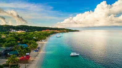 Boats on carribean blue water near a shoreline of Roatan Honduras
