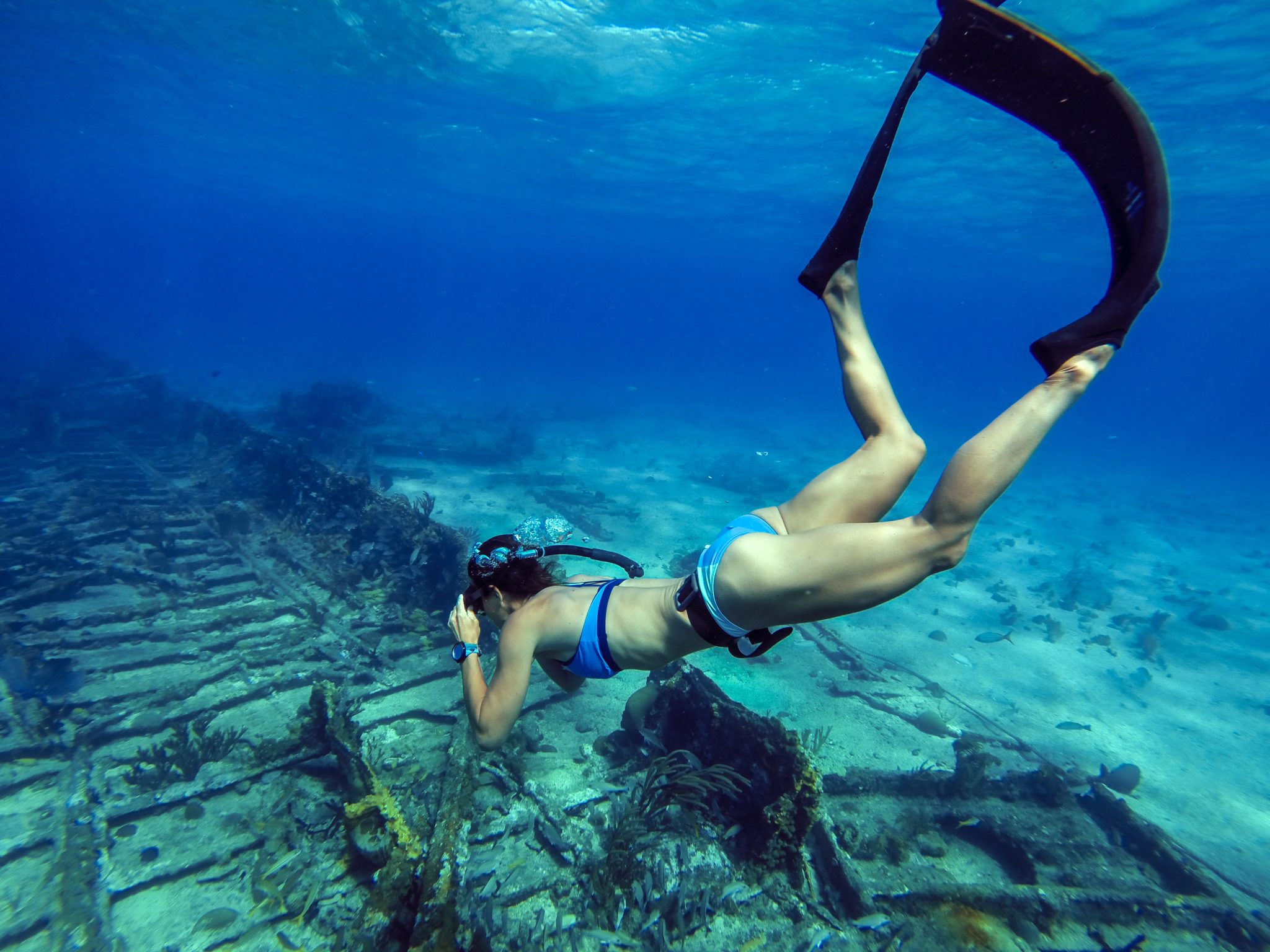 A female freediver swims down to a shipwreck in the Bahamas but freediving is one of many things not to do after scuba diving