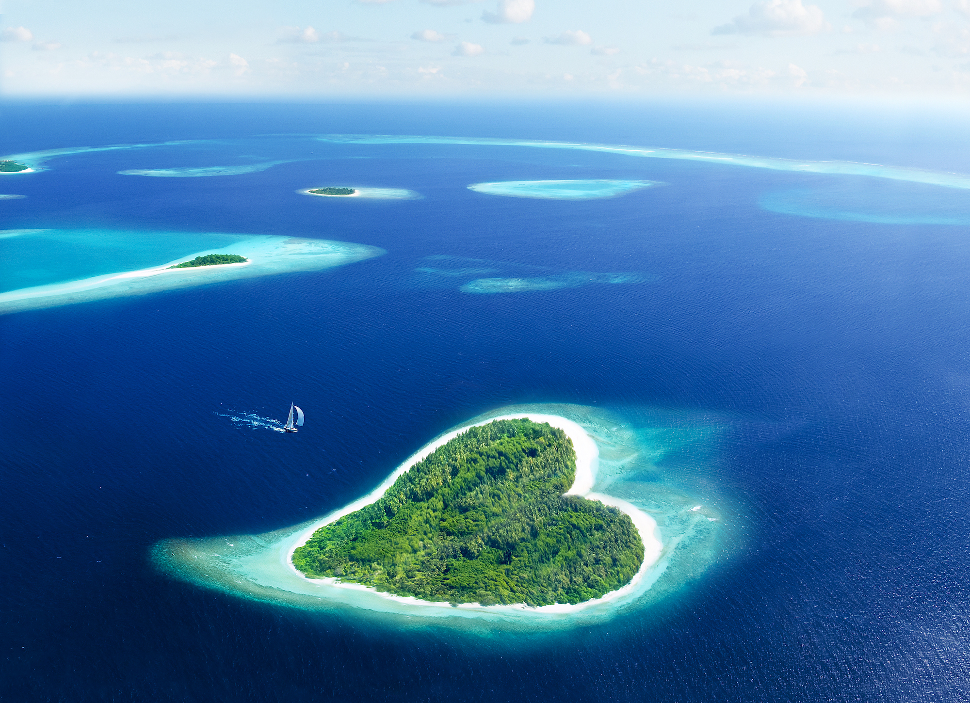 A lush heart-shaped island in the middle of deep blue ocean, which is the perfect spot for a romantic scuba diving vacation