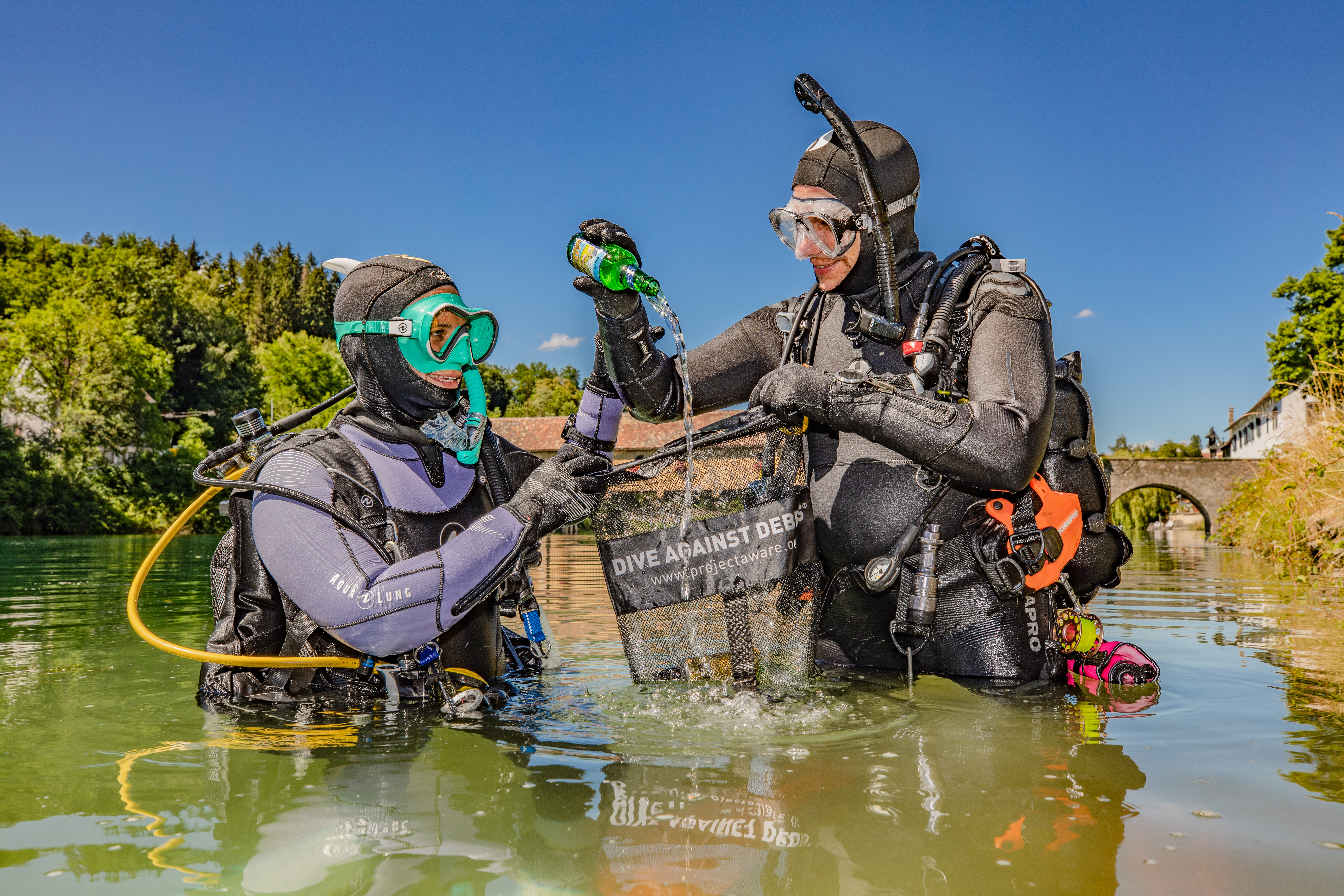 두 명의 다이버가 잔해에 맞서 다이빙을 하고 있습니다. 잔해가 가득한 가방을 들고 수면 위로 올라왔습니다. 