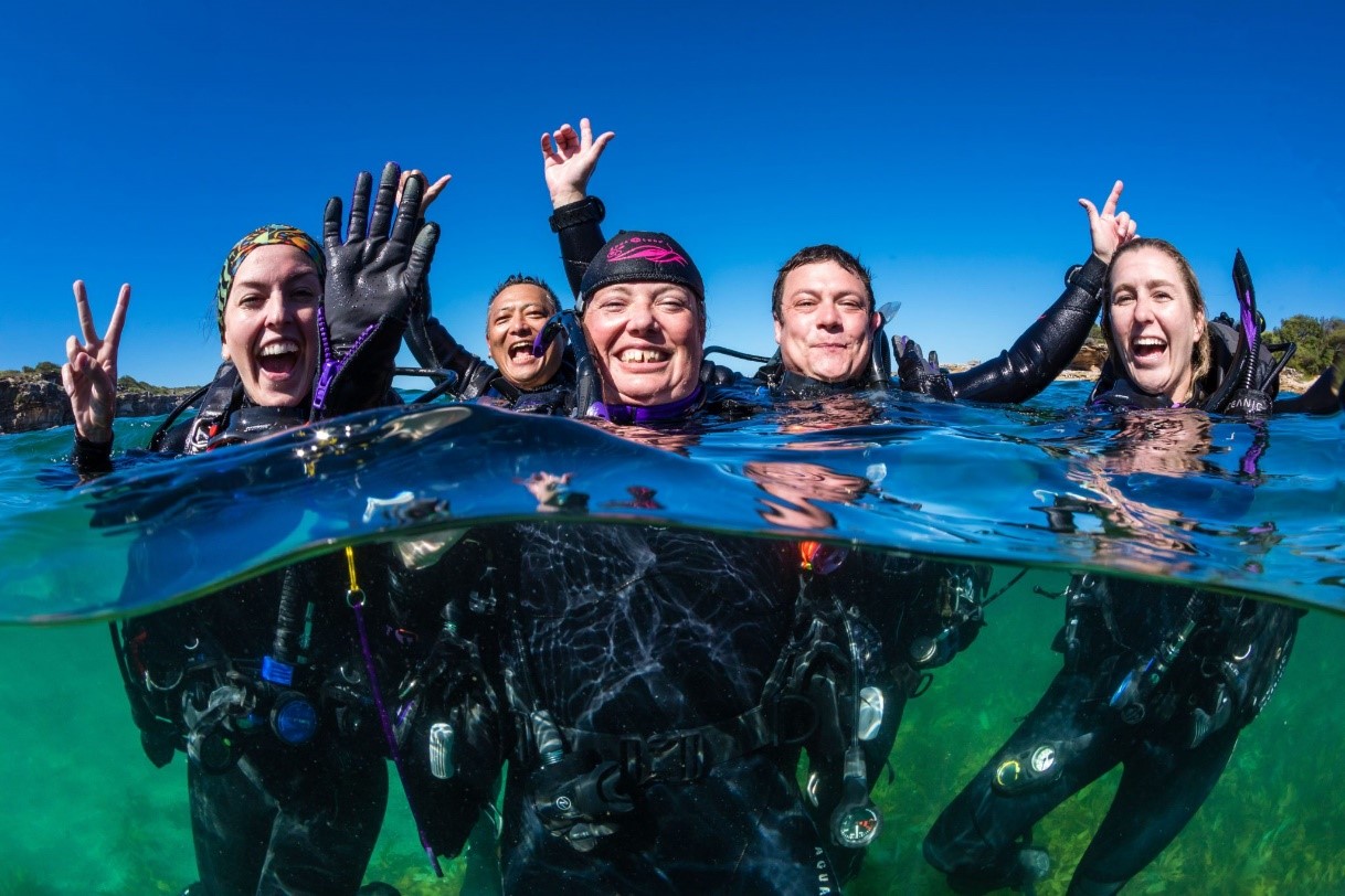 Happy scuba divers on the surface, and who found out 'why book with PADI Travel' after getting great benefits on a group trip