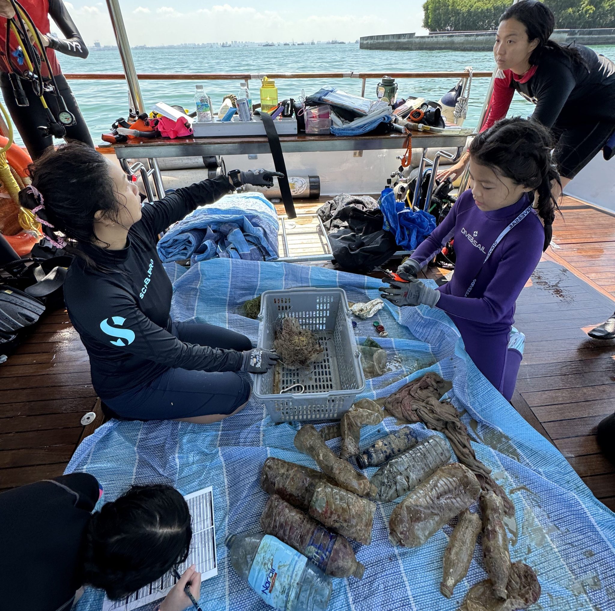 在「女性潛水日」的清理潛水活動結束後，4名女性潛水員在船上分類塑膠廢棄物