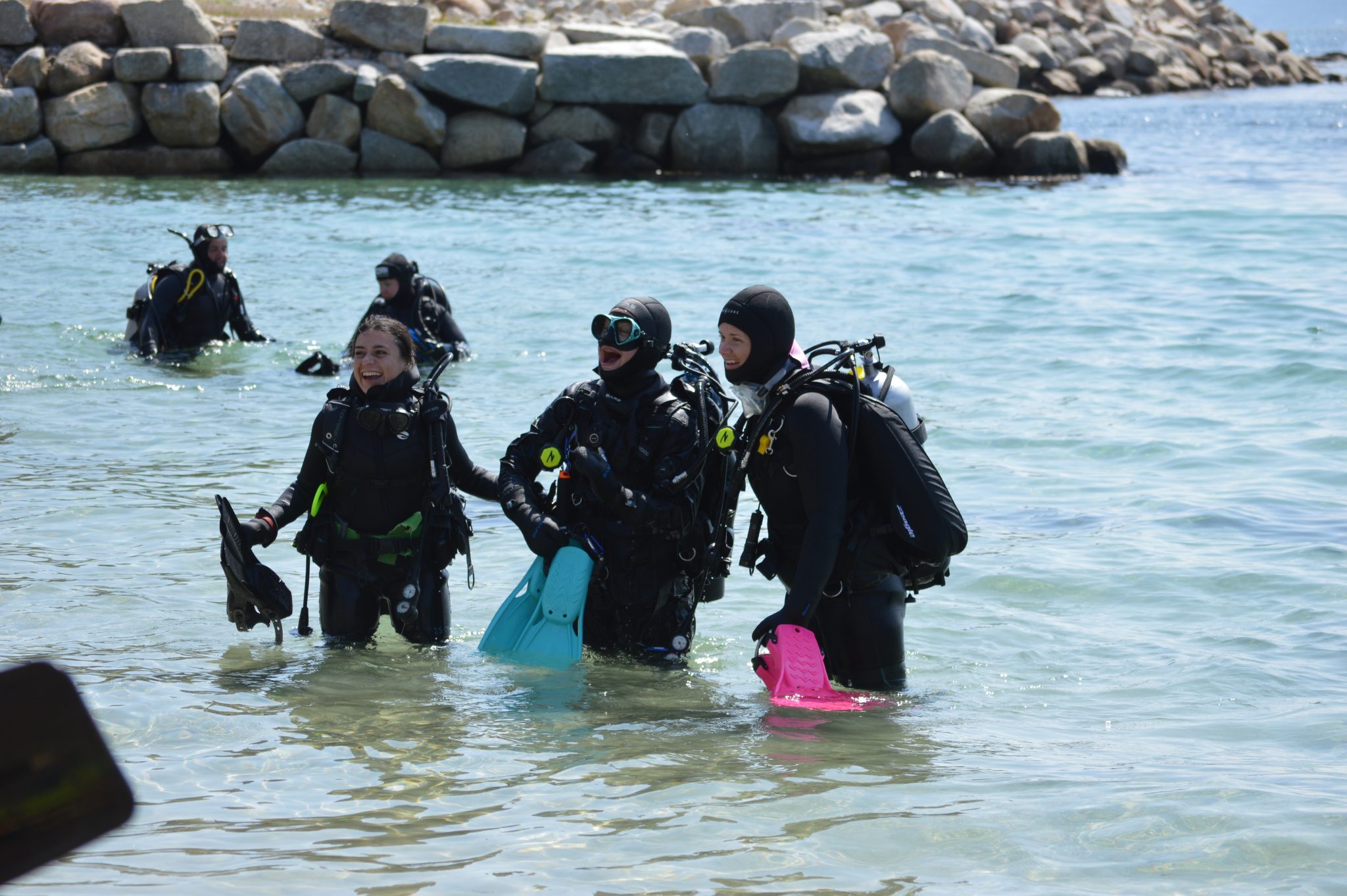三名女性潛水員身著全套裝備，在「2026年女性潛水日」活動中結束岸潛後浮出水面