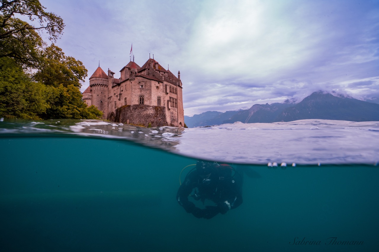 a diver swims under a chateau in switzerland