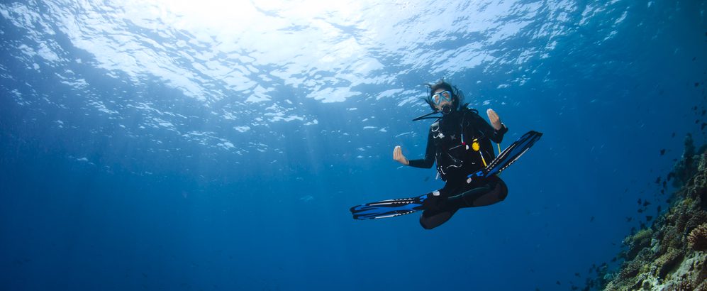A scuba diver posing in the lotus yoga pose, enjoying underwater meditation benefits and Peak Performance Buoyancy