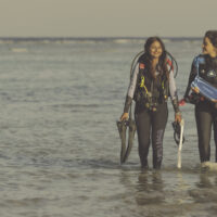 two women exit the water by shore after a dive in the Red Sea