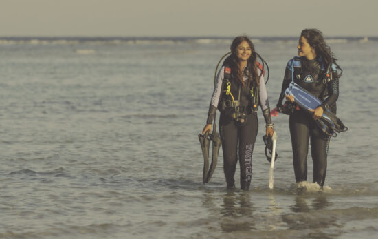 two women exit the water by shore after a dive in the Red Sea