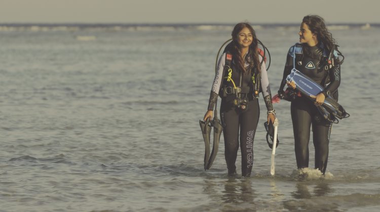 two women exit the water by shore after a dive in the Red Sea
