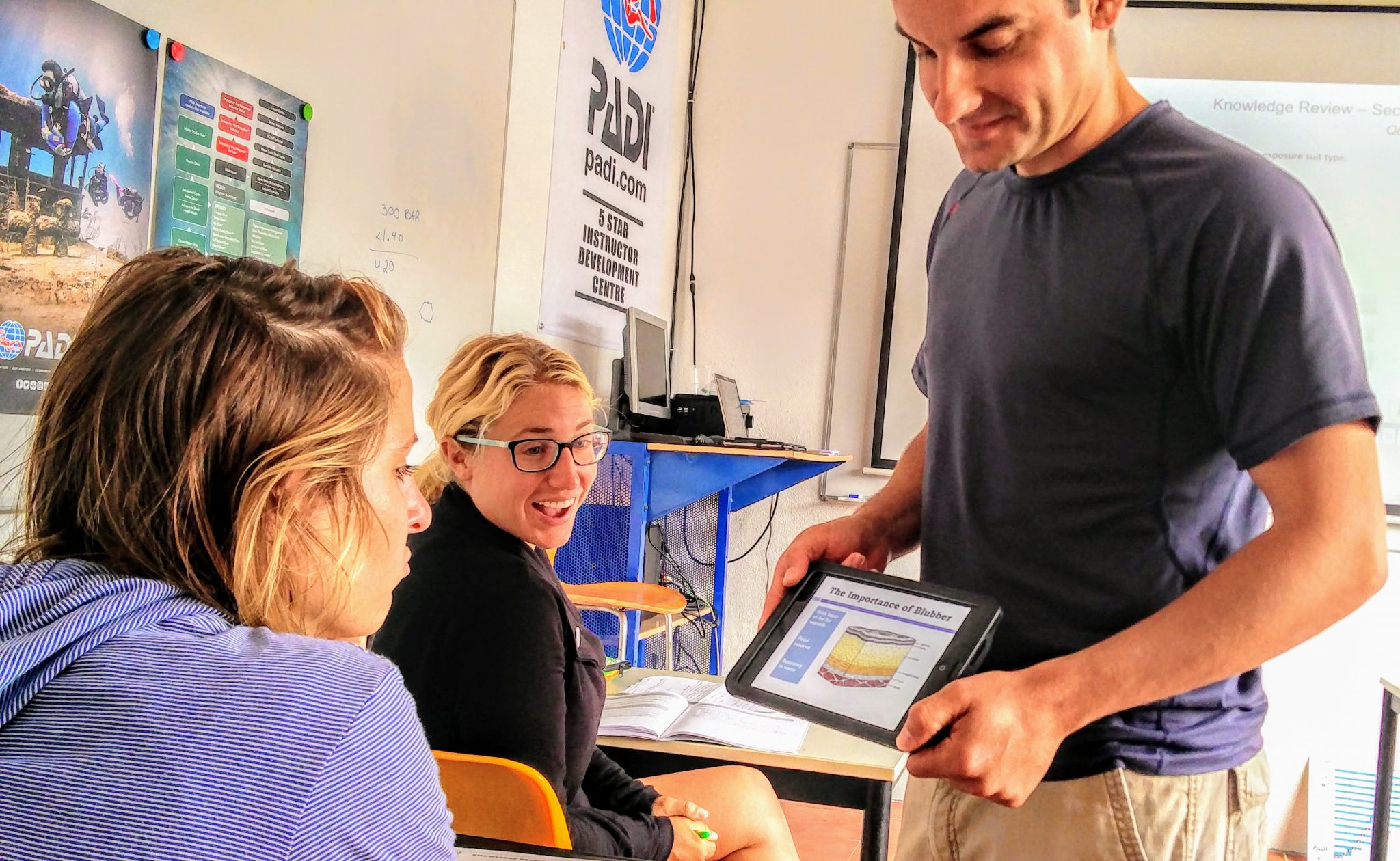 A PADI Instructor explains PADI dive theory to a group of Open Water Diver students who have chosen to learn in the classroom