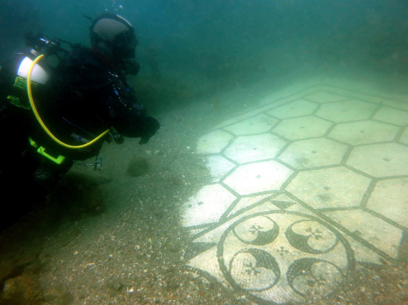 A scuba diver uncovers a mosaic floor in the ancient sunken city of Baia, a famous underwater museum in Italy