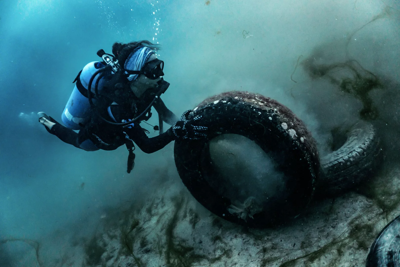 Ein Taucher entfernt einen Reifen unter Wasser Dive Against Debris