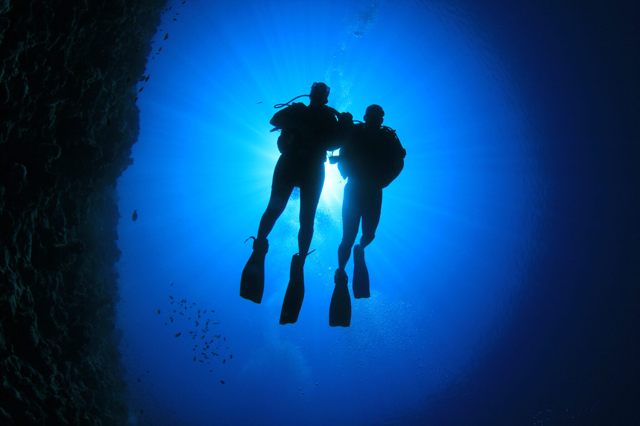 The silhouette of two scuba divers underwater, who may also be dating after using one of many ocean themed pick up lines