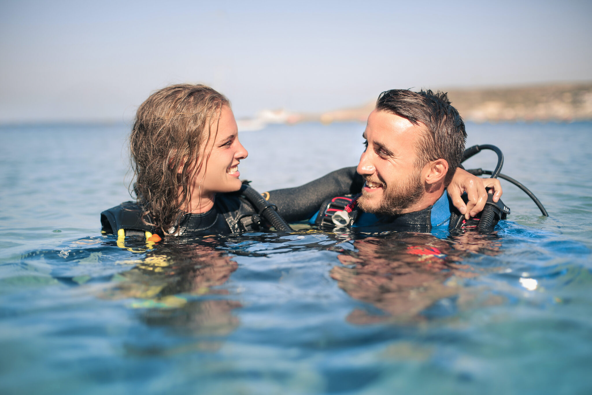 Two scuba divers talking and laughing on the surface as they share the same passion, one of the benefits of dating a diver