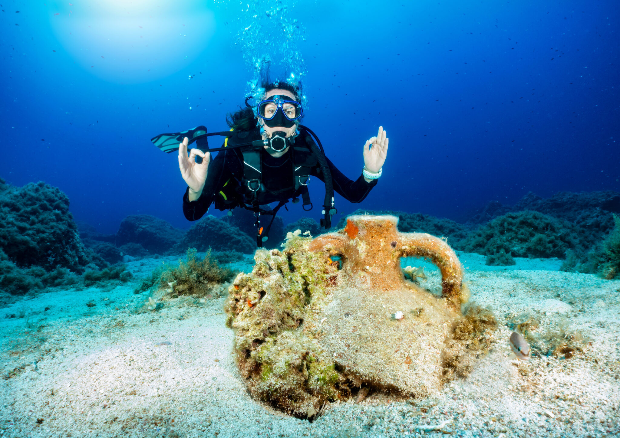 A diver looking at an ancient amphora and one of many attractions in Greece, one of the best places to get scuba certified