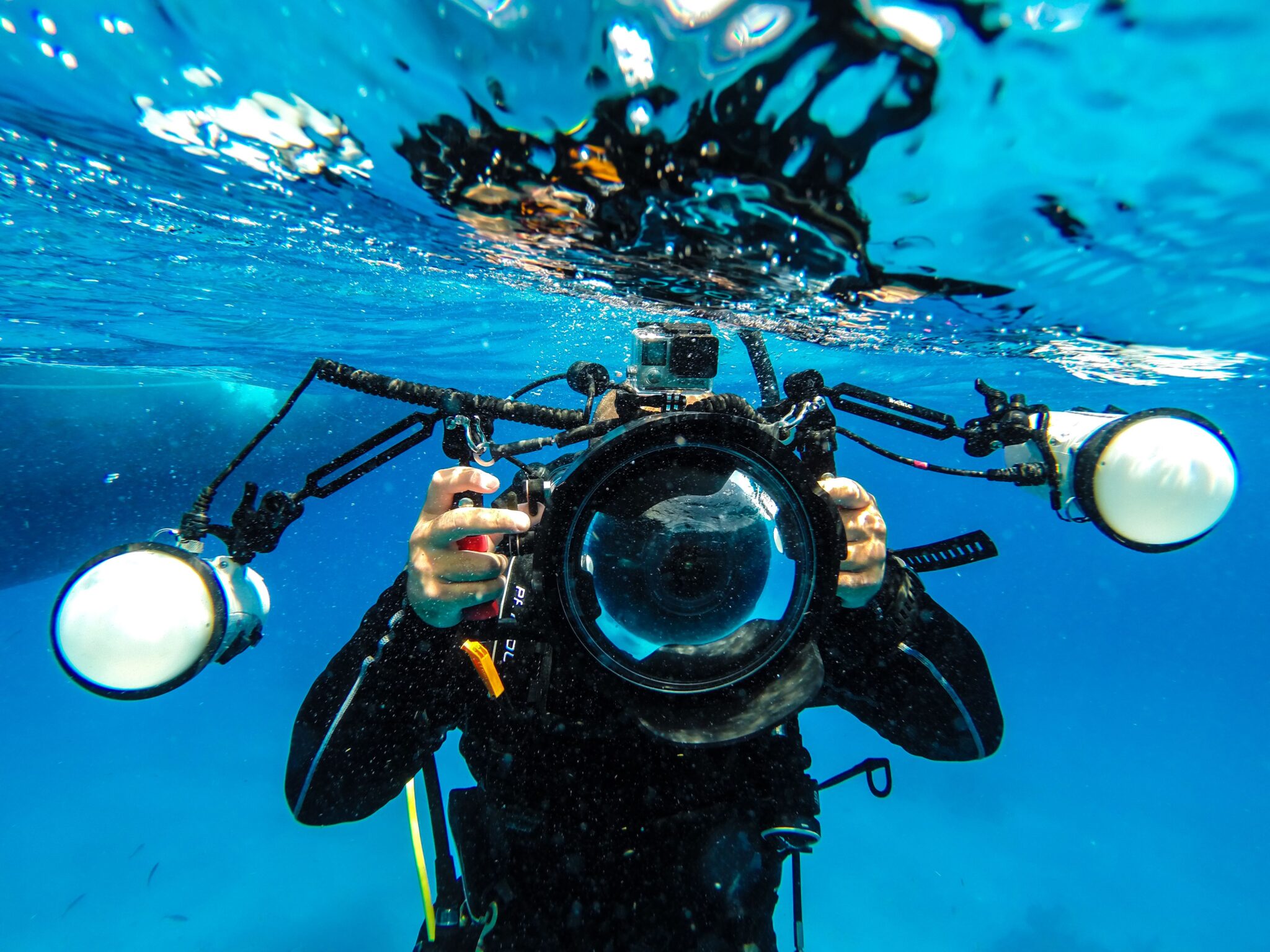 A scuba diver holding a camera and strobes who hopes to find colorful nudibranchs which are popular with macro photographers