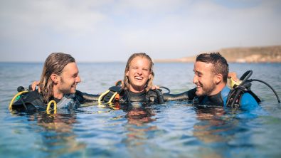 three scuba divers at the surface