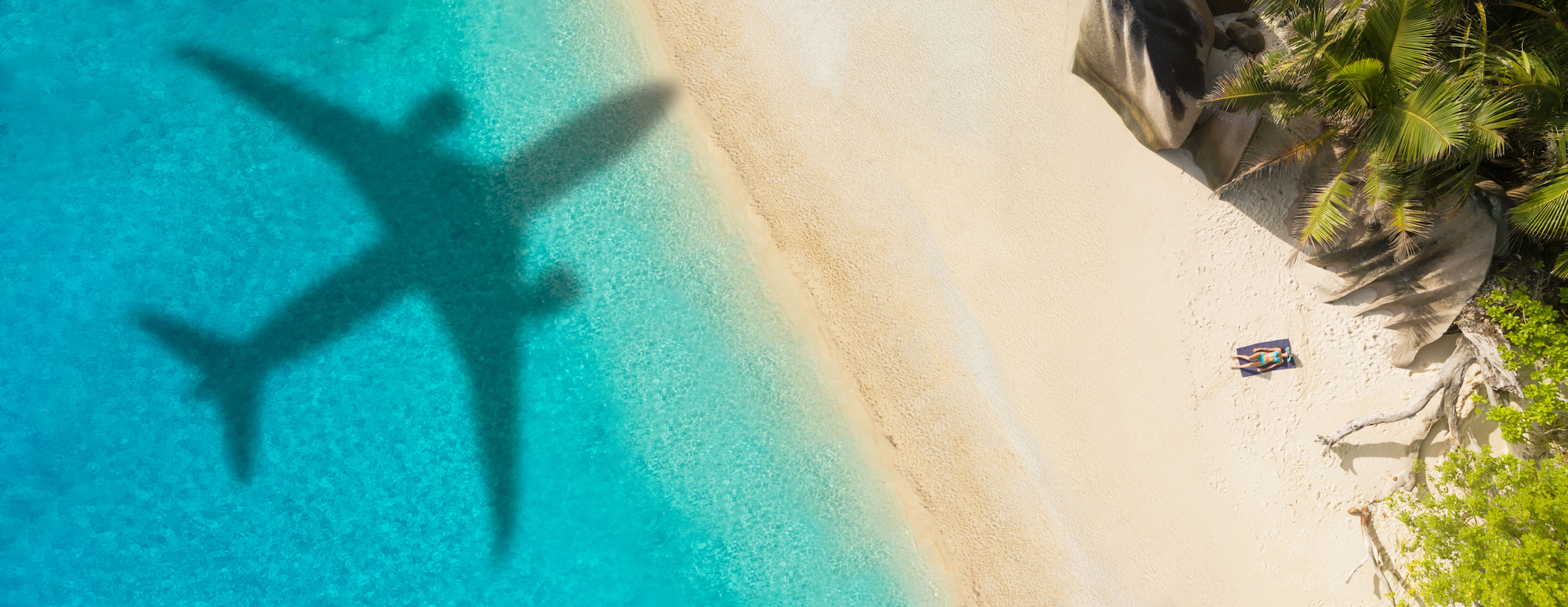 A shadow of an airplane flying over one of many all-inclusive scuba resorts that can be booked with PADI Travel