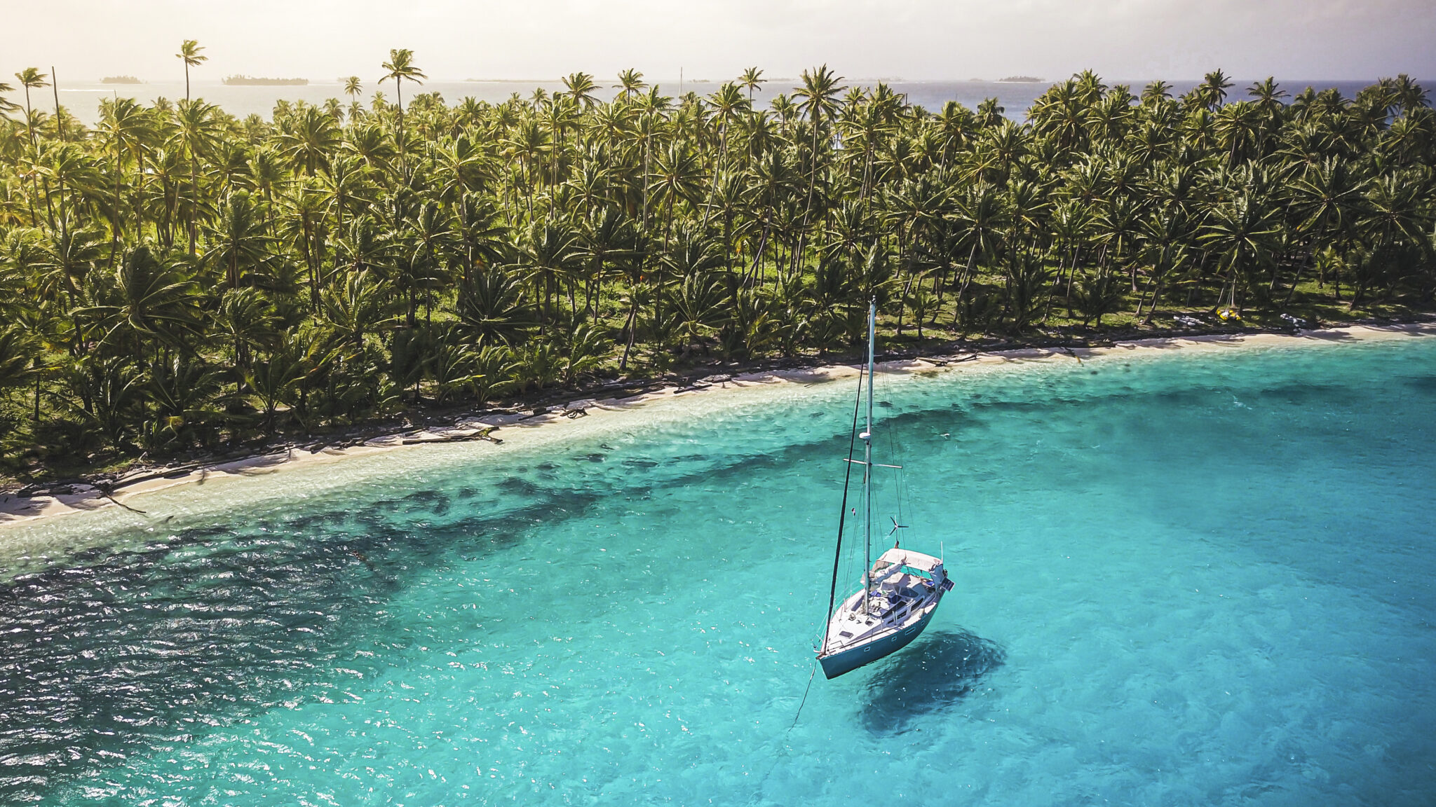 A scuba diving boat anchored in crystal clear azure water, which provides excellent tropical liveaboard diving for beginners