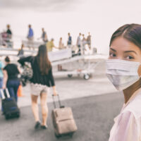 COVID-19 Travel Airport Asian woman tourist boarding plane for holiday wearing face mask. PPE Corona virus Coronavirus negative test and vaccine.