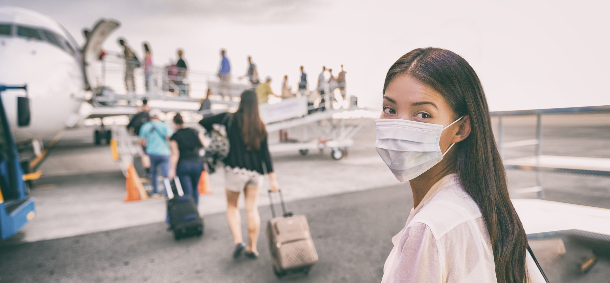 COVID-19 Travel Airport Asian woman tourist boarding plane for holiday wearing face mask. PPE Corona virus Coronavirus negative test and vaccine.