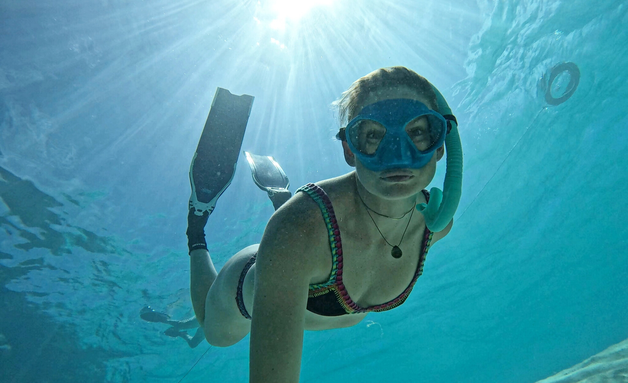 Heather Stringer freedives into the clear ocean while wearing Tula Blue jewelry