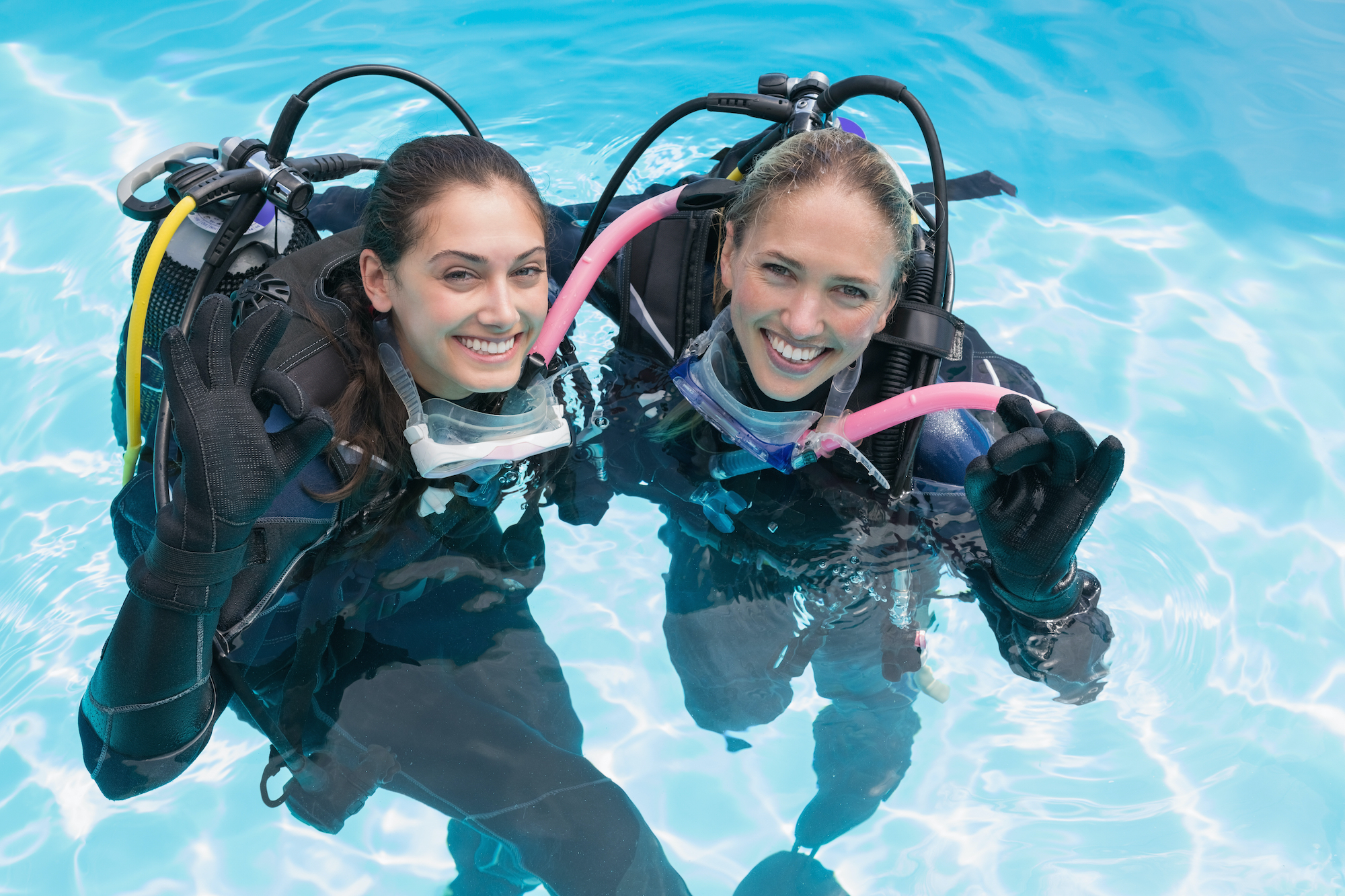 Two happy female divers in the swimming pool, who have completed their Confined Water Dive while learning to dive