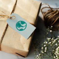 A package gift wrapped in brown paper with a gift tag that has a picture of the earth on it