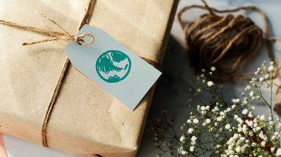 A package gift wrapped in brown paper with a gift tag that has a picture of the earth on it