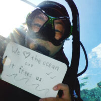 Diver holding a sign that says "We