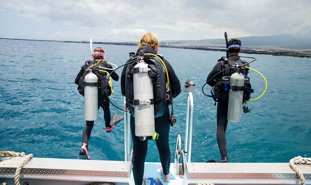 three divers take a giant leap off the back of a boat