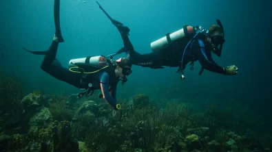 two divers swim underwater in Curacao using good trim
