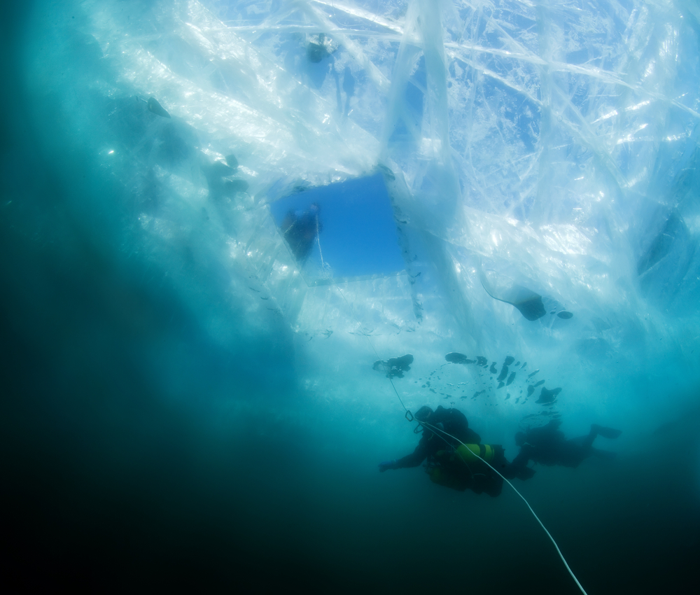 Scuba divers diving beneath the ice, an activity that's only possible because H20 can take the form of both liquid and solid