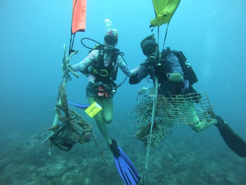 Two divers use lift bags to bring up marine debris.