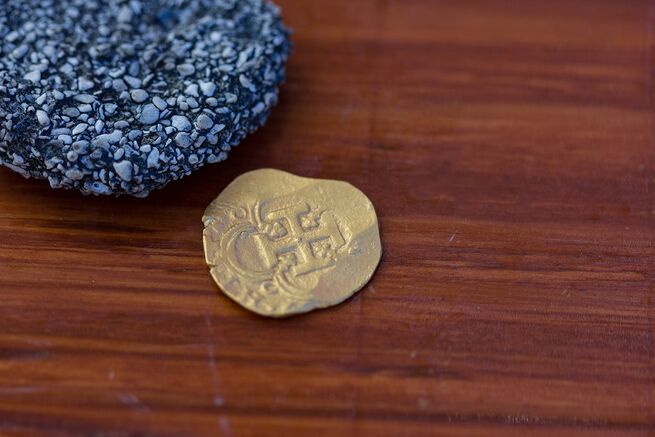 A gold coin recovered from the wreck of the Atocha sitting on a desk.