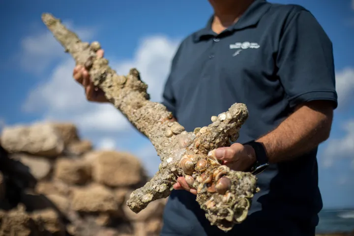 A man holding a 900-year-old encrusted sword, found while diving for treasure and one of many ancient discoveries by divers