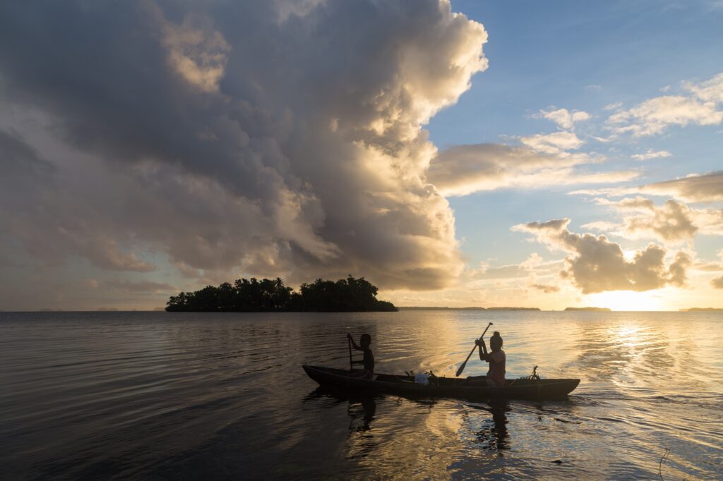two people in a canoe at sunset in the solomon islands