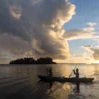 two people in a canoe at sunset in the solomon islands