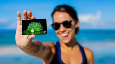 a woman holds out her PADI certification card showing a nudibranch