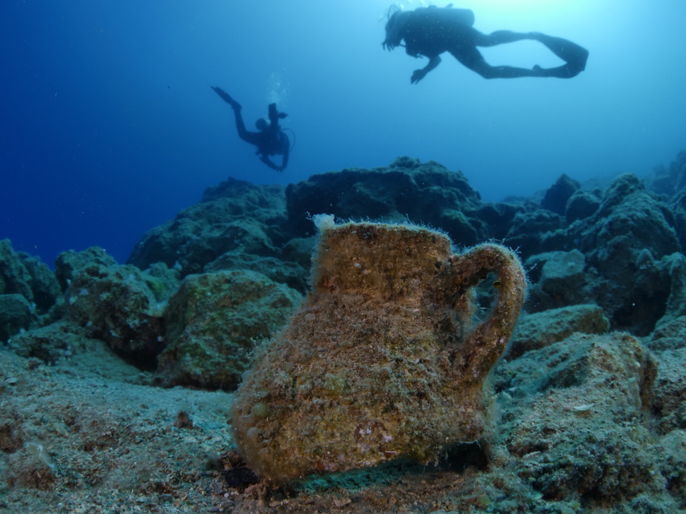 two divers float over archeological artifacts in Greece