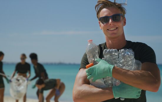 A young man in sunglasses cleans up plastic from a beach for citizen science