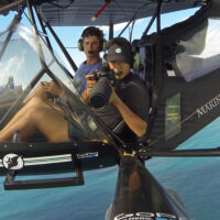 a marine scientist in a helicopter over the ocean holding a camera